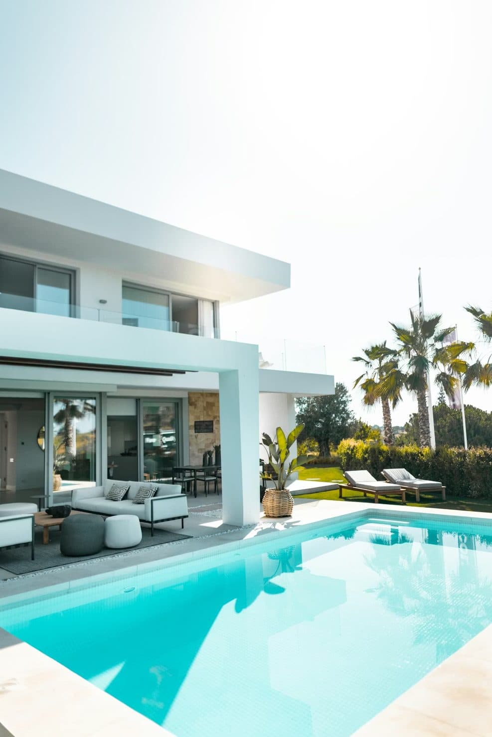 Poolside lounge chairs beside a modern vacation home