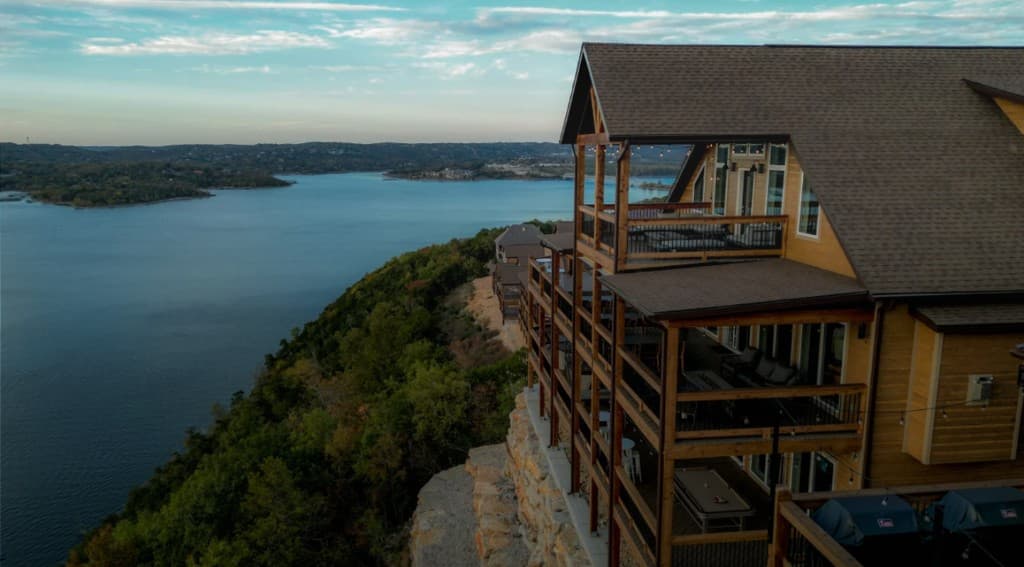 Cliffside vacation rental at sunset overlooking a lake and forested hills